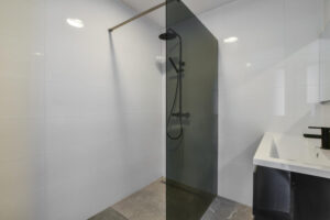 Bagno di design sui toni del grigio e del nero, con doccia walk-in moderna